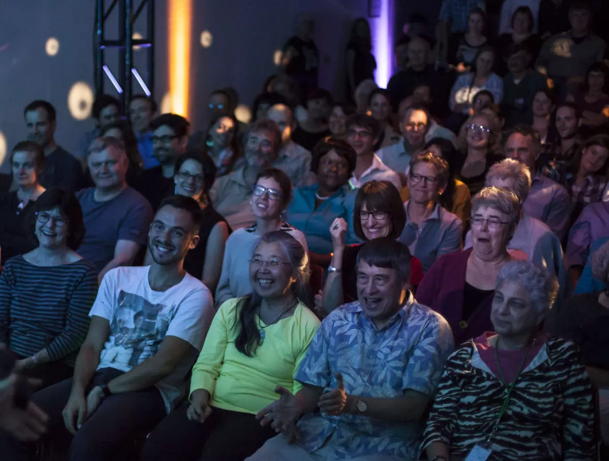 Several rows of audience members laughing