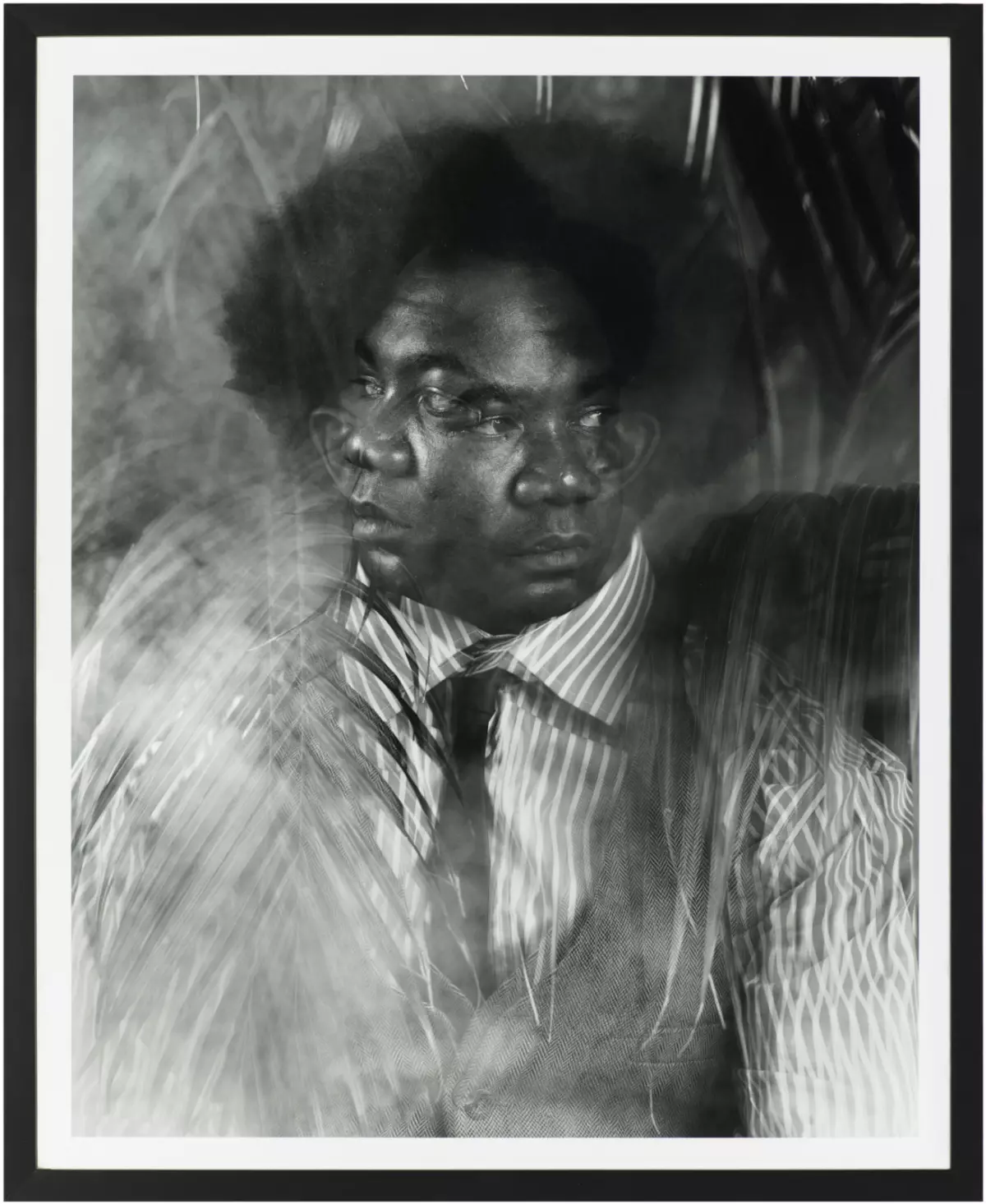 This black-and-white vertical portrait portrays a dark-skinned person with two faces, one looking left and the other looking right, with palm-like fronds surrounding the figure.