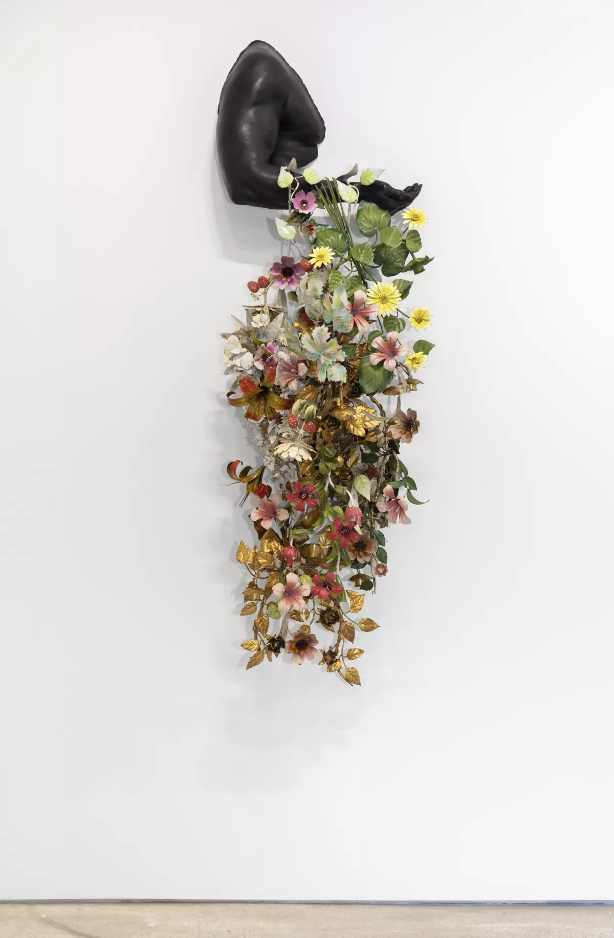 a flowing bouquet of flowers is draped over the sculpture of a man's arm