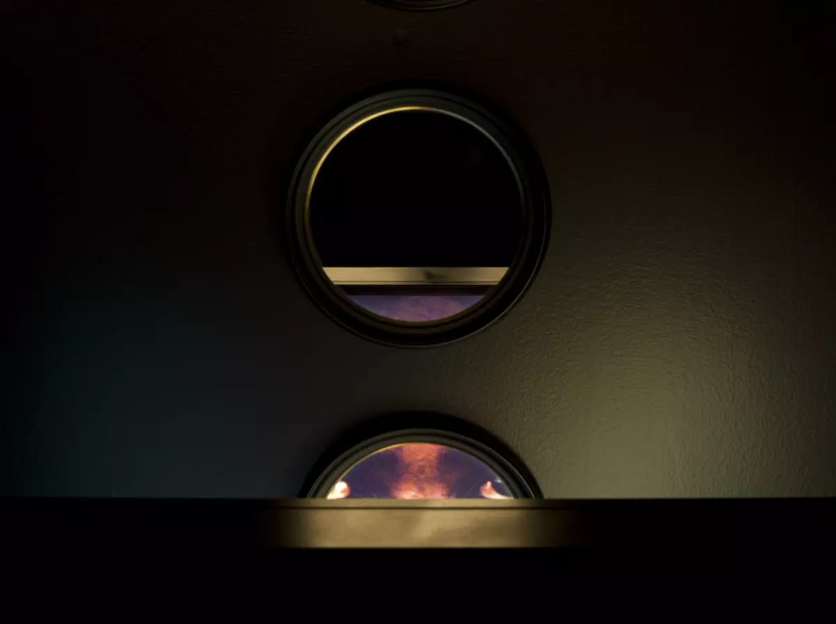 A dark view of a lightbox showing circular mirrors reflecting abstract colors of orange and purple