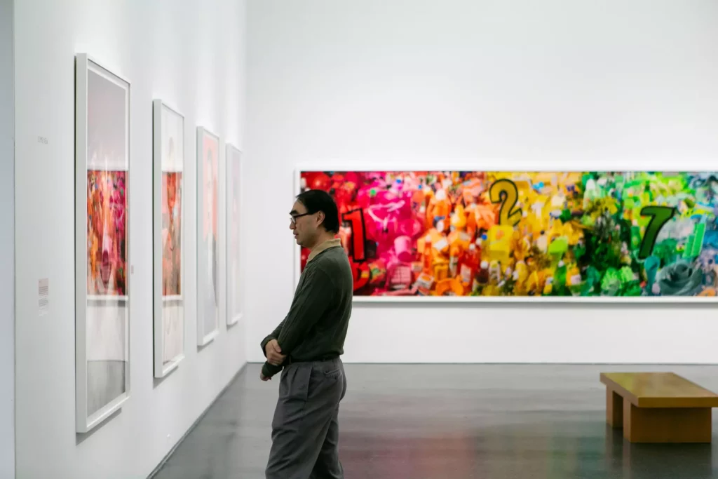 A man stands in profile intently browsing art in gallery