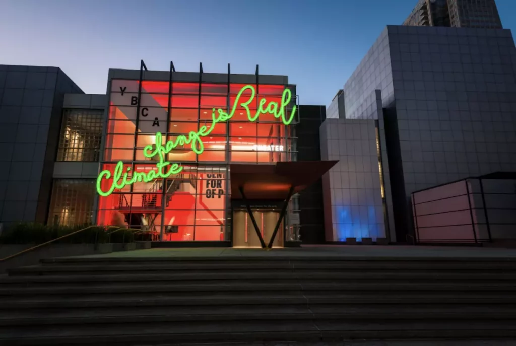 exterior of building with large neon cursive handwriting with the text climate change is real