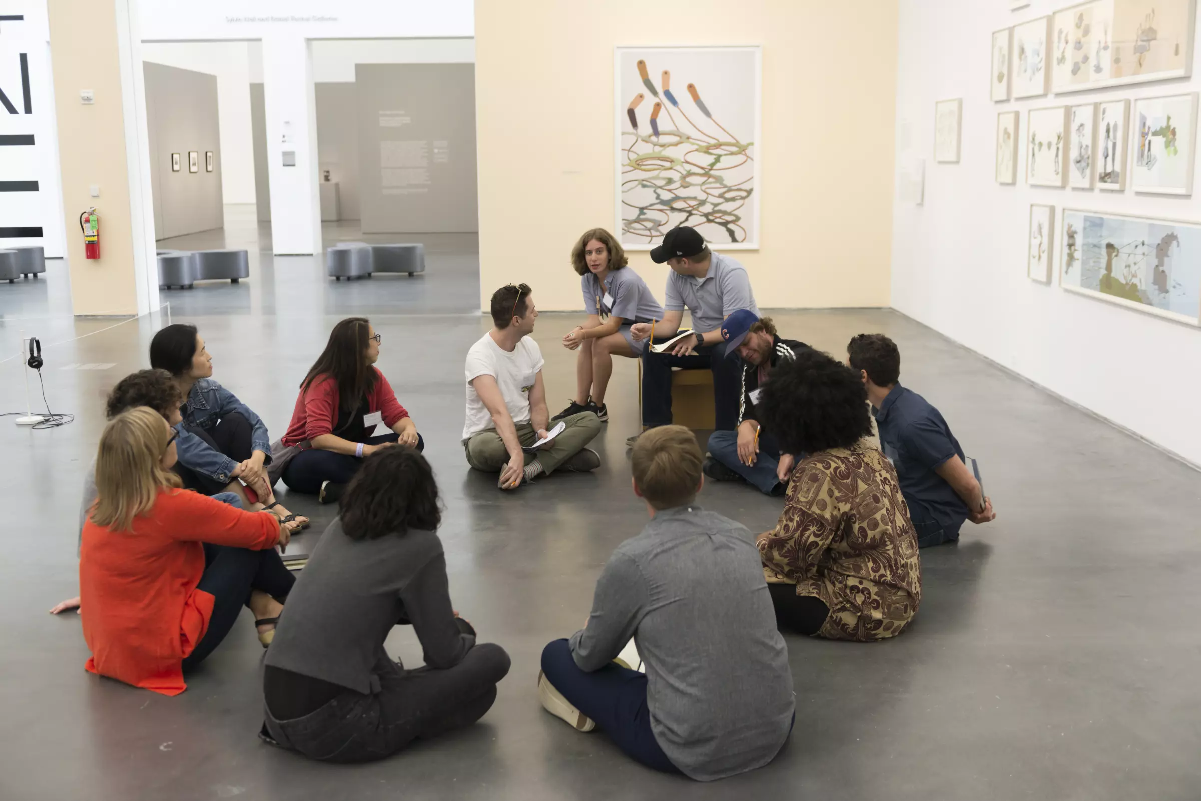 A group sitting on floor in a circle within a gallery space