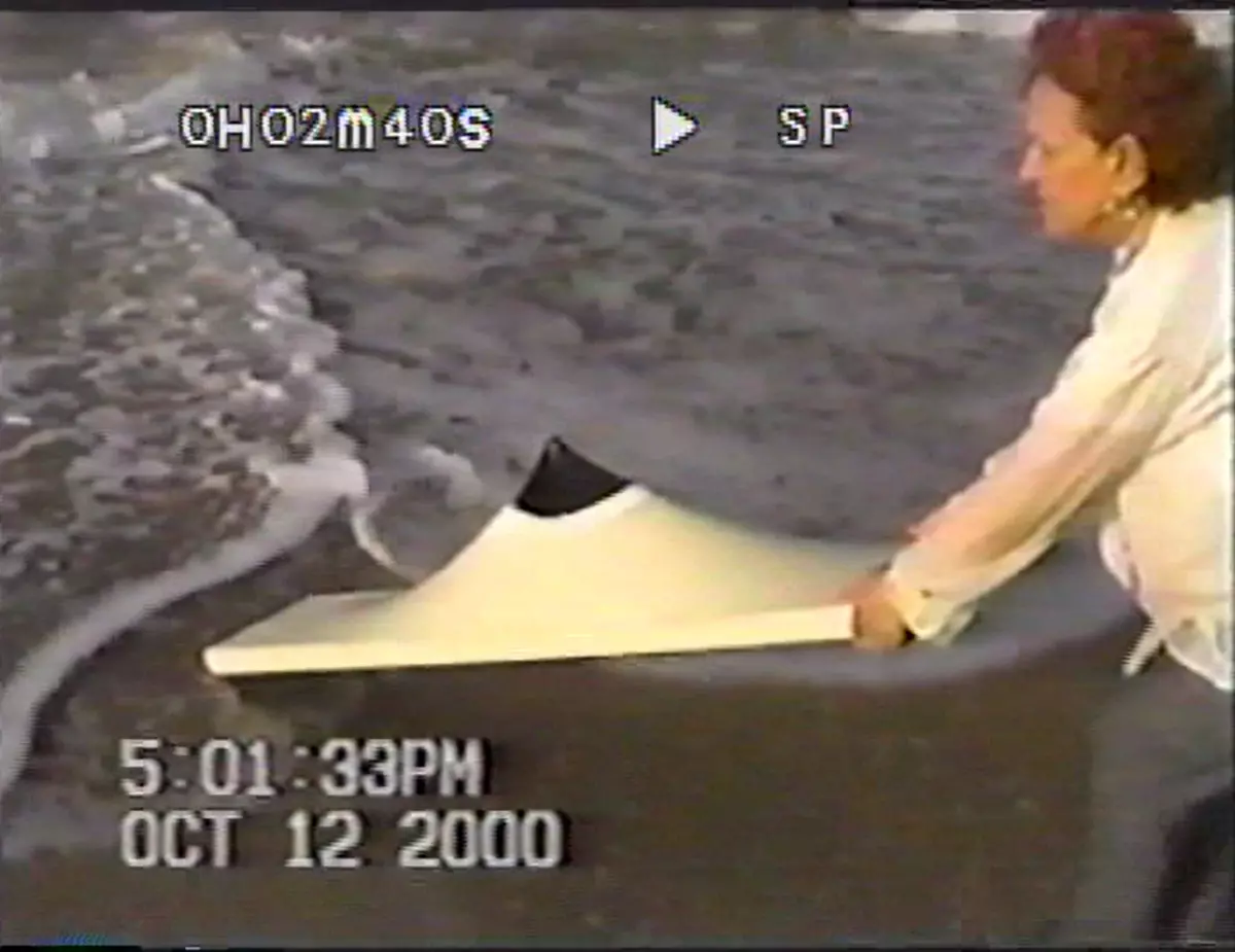 Video still of woman placing object into ocean