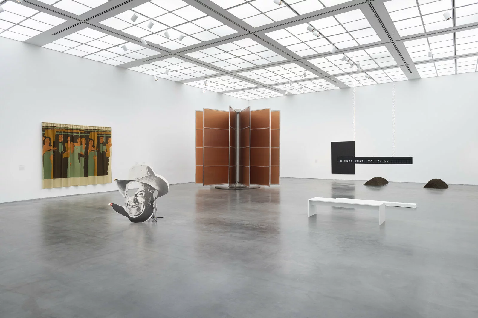 Large, white gallery space with six artworks visible. Two are hung on walls; four are installations.