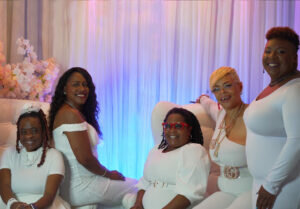 Five black woman of varying ages dressed in white