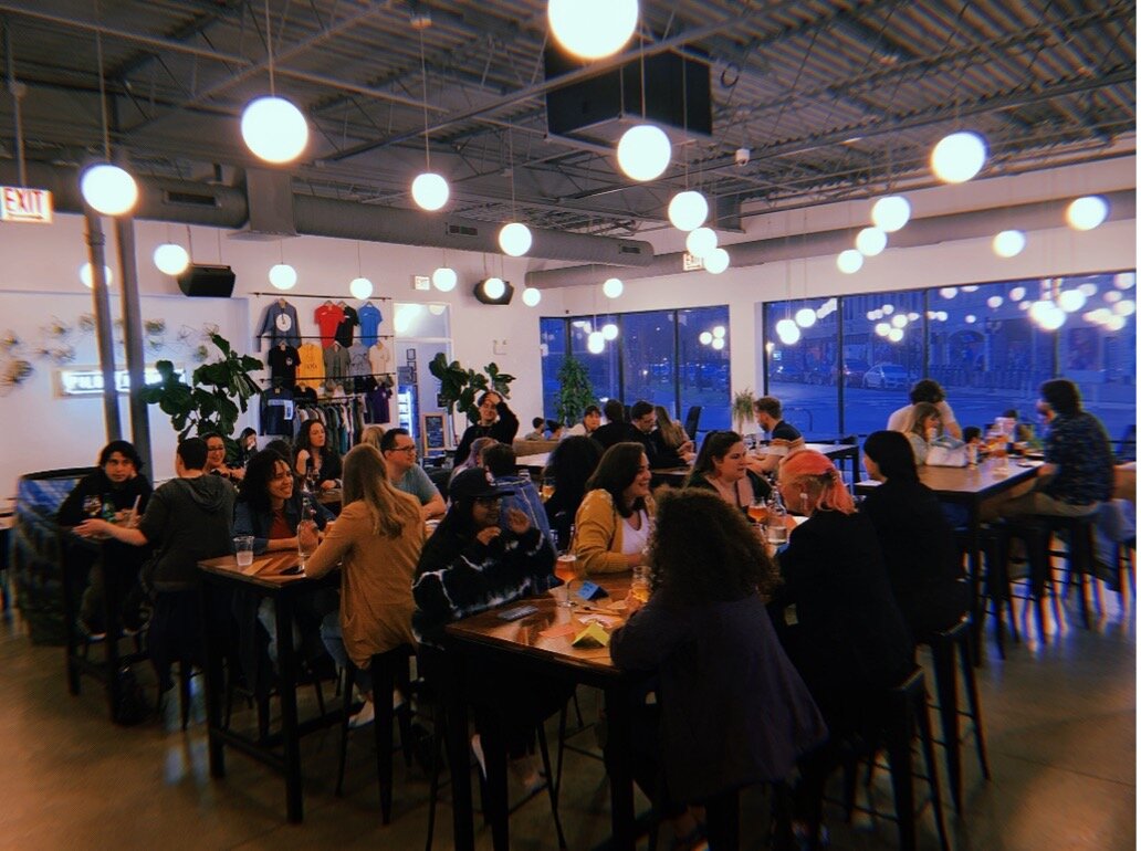 A room filled with people sitting at several different tables.