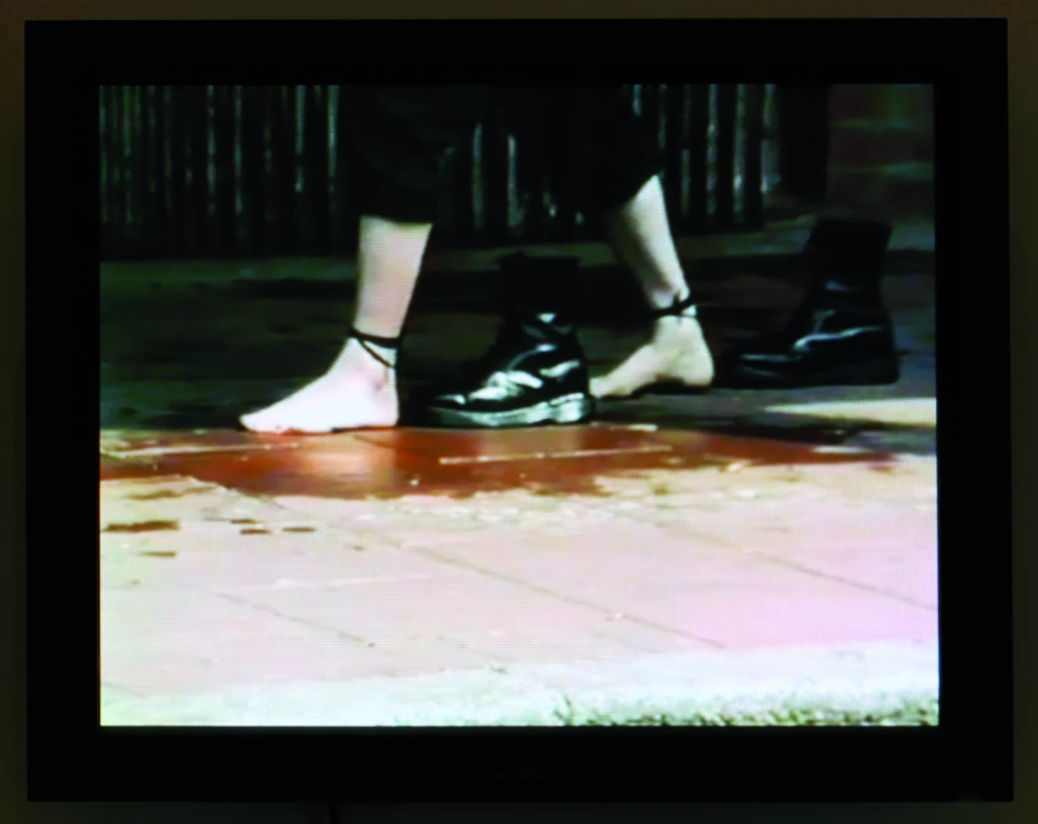 Still shot of woman's bare feet and a pair of black boots.