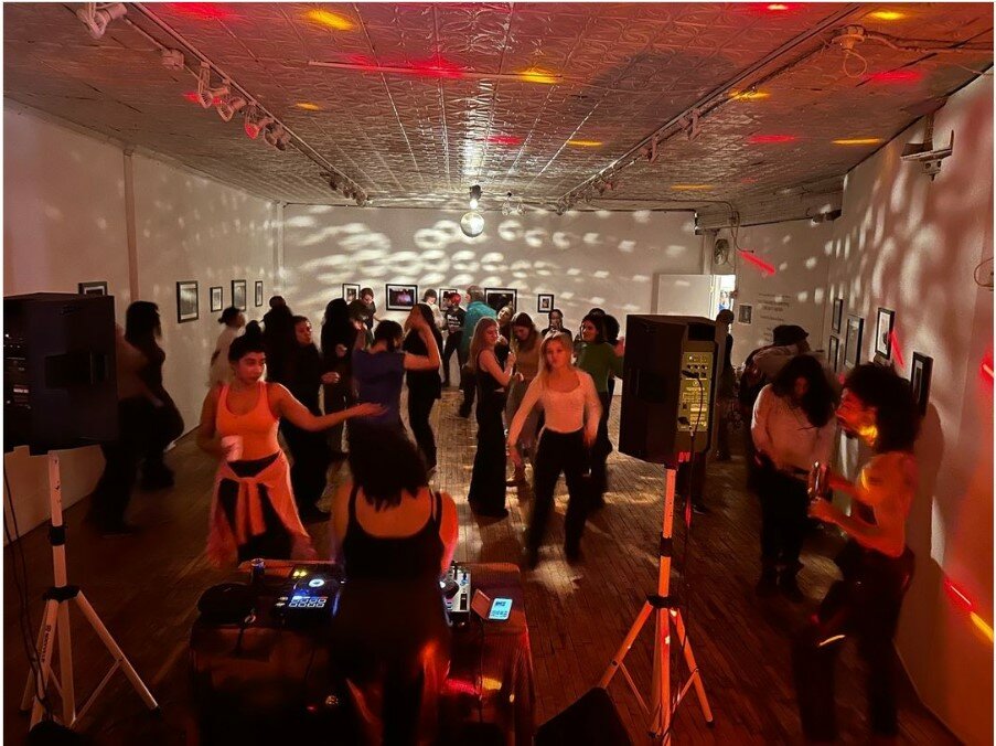 Group of people dance in a large room.
