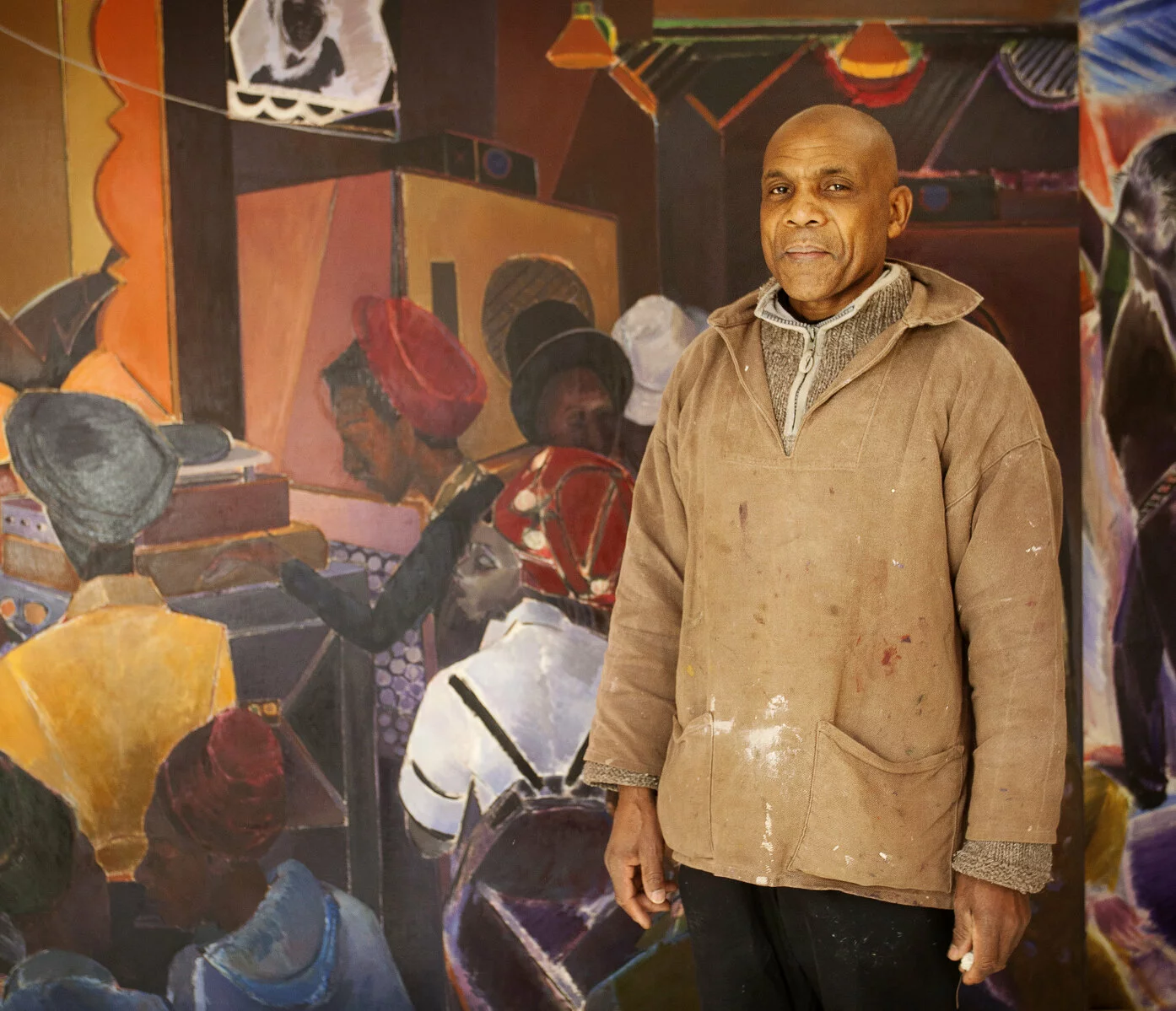 Photo of artist Denzil Forrester standing in front of his painting.