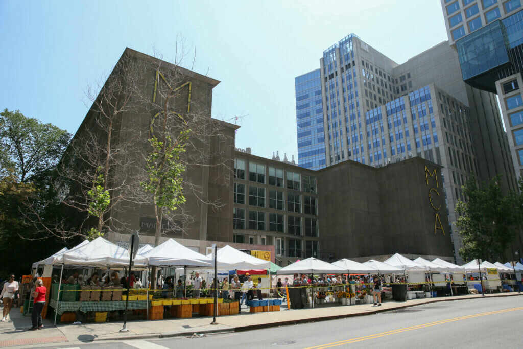 The MCA's plaza covered with pop-up white vendor tents filled with flowers and produce.