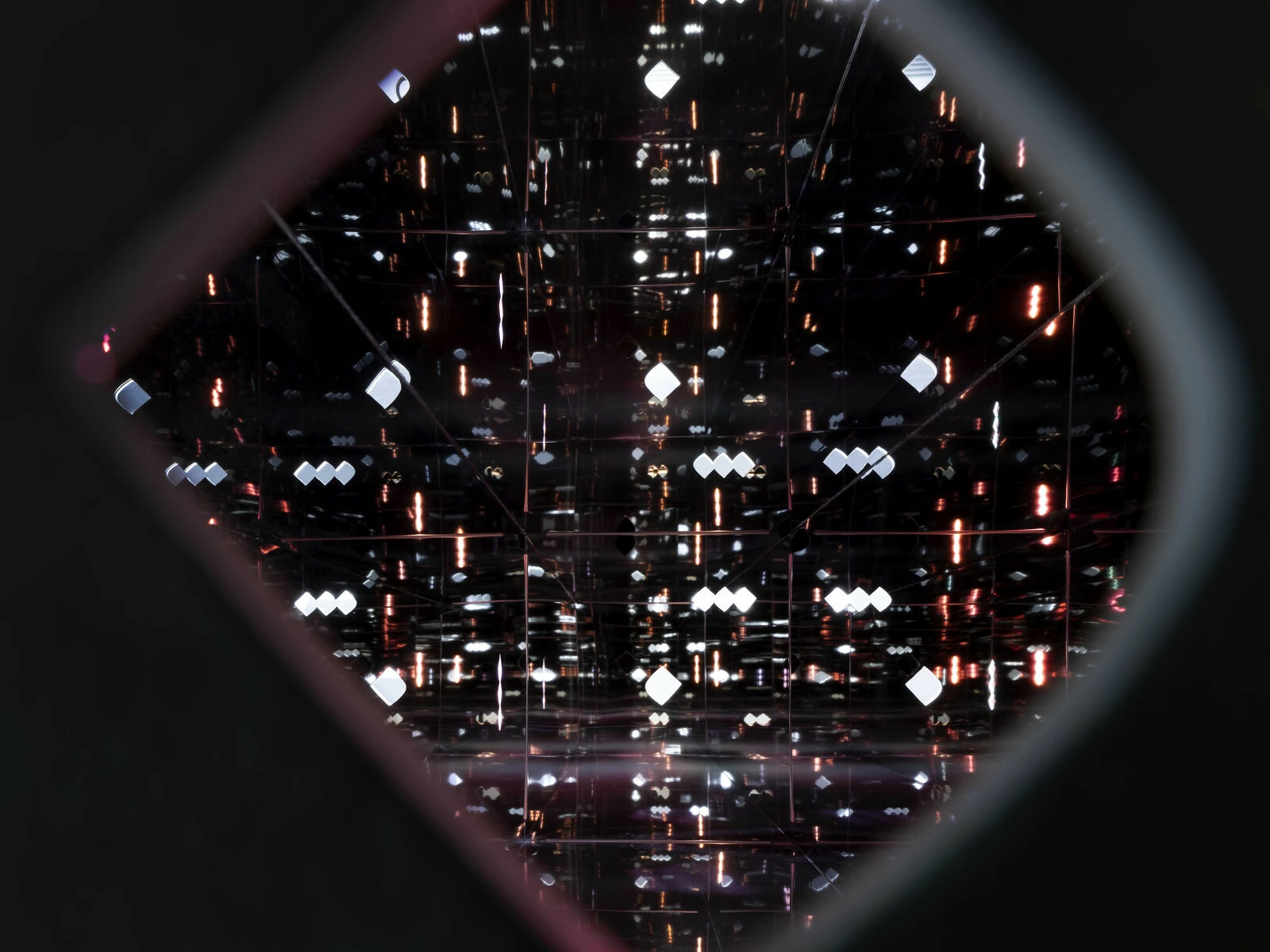 View through a diamond shape, a noghte, reveals millions of light refractions in the shape of more noghtes.
