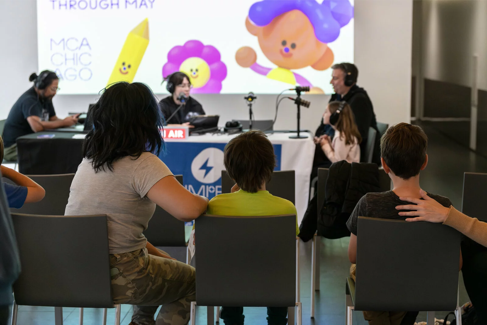 A group of people sit watching a live radio show.