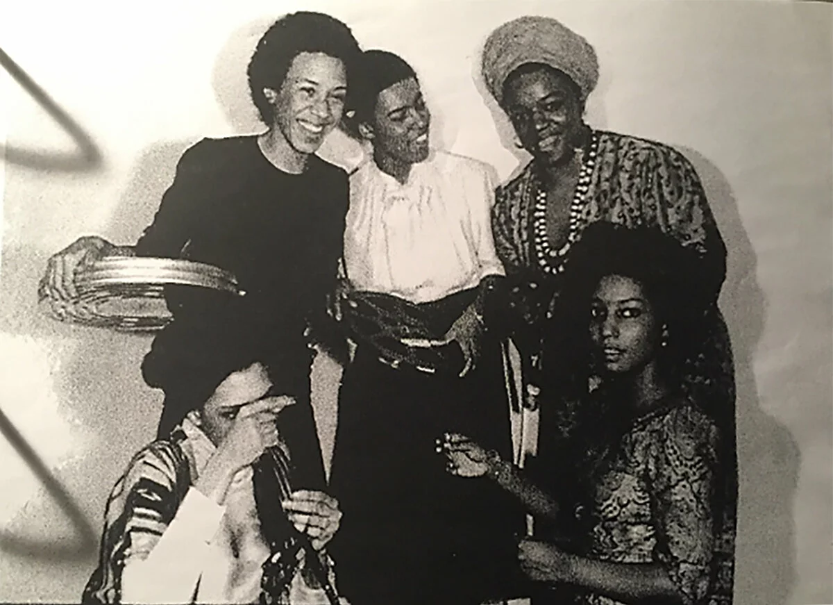 Black-and-white archival photograph of five women arranged in a semi-circle holding film and film canisters.
