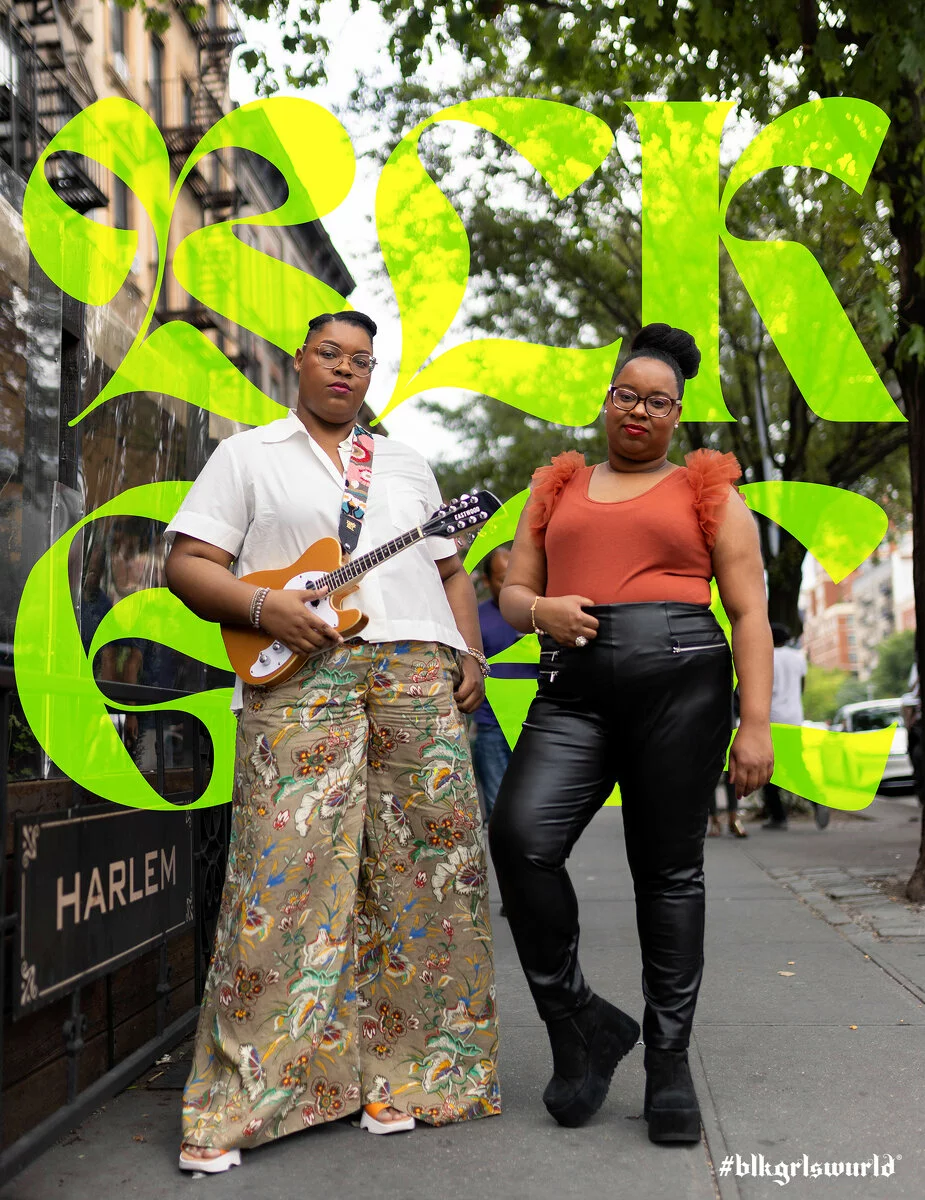 Portrait of two people on a street next to a sign labeled Harlem. One of them holds a guitar.