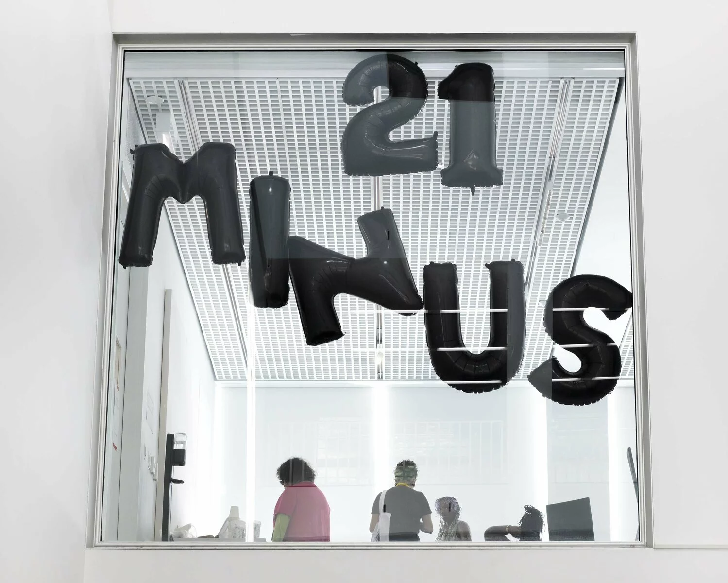 A square window with balloons that spell out 21 Minus