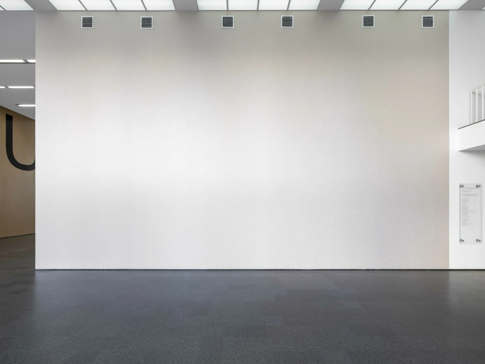 A seemingly off-white wall in an empty, airy space.