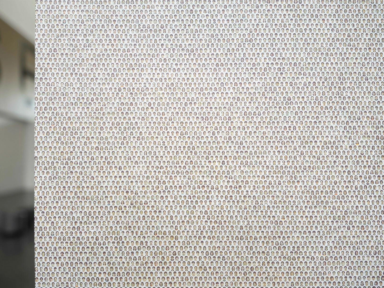 A corner of a wall filled with a wallpaper of dots made from drawings of people's faces.