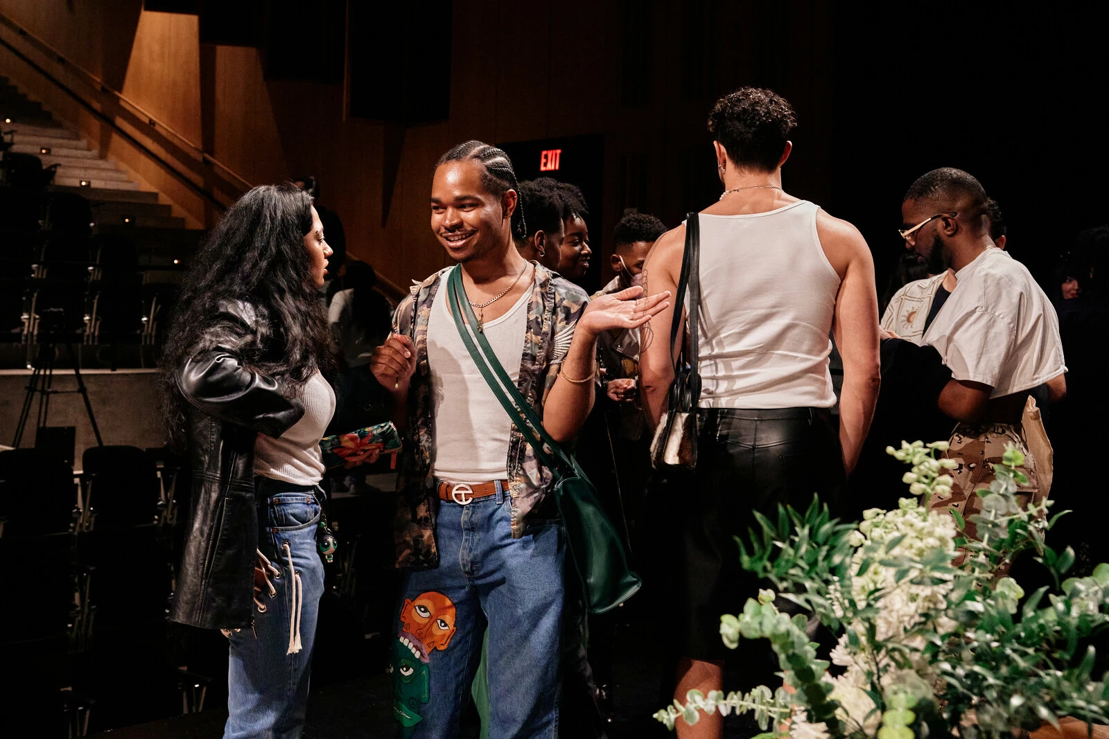 Five people gather on stage wearing leather jackets, white tank tops, and blue jeans.