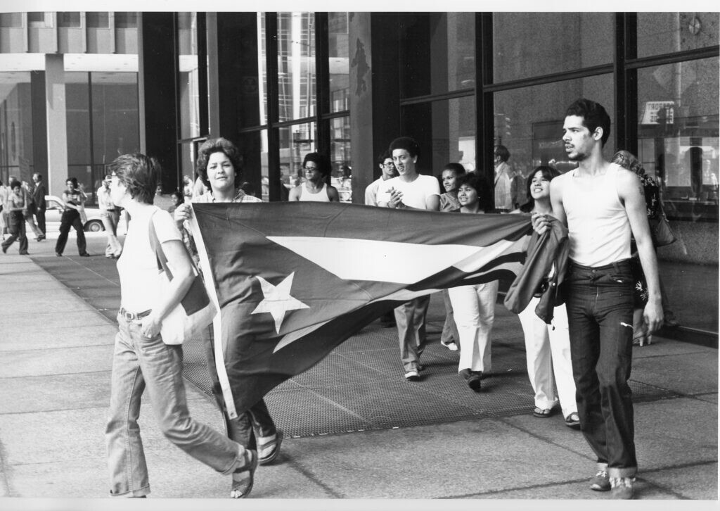 Black-and-white photo of a group of people carrying the Puerto Rican flag.