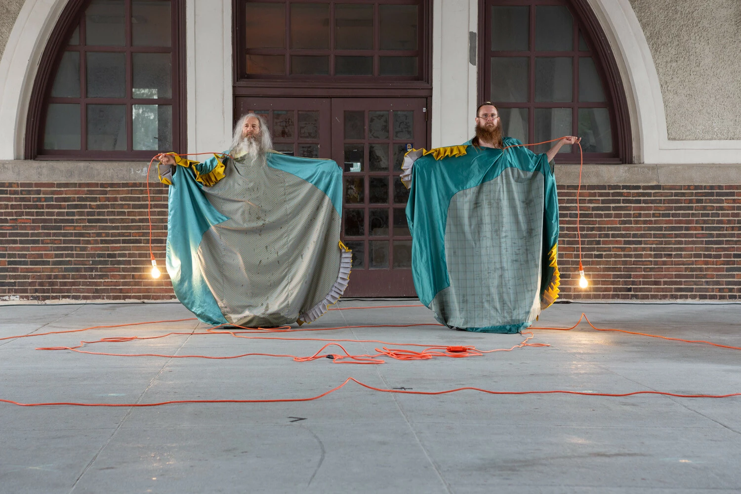 Performance still featuring two performers in costume holding rope lights.