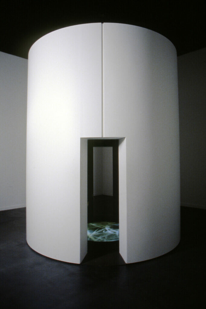 A thin doorway leads to a built-out cylindrical room with an artwork inside