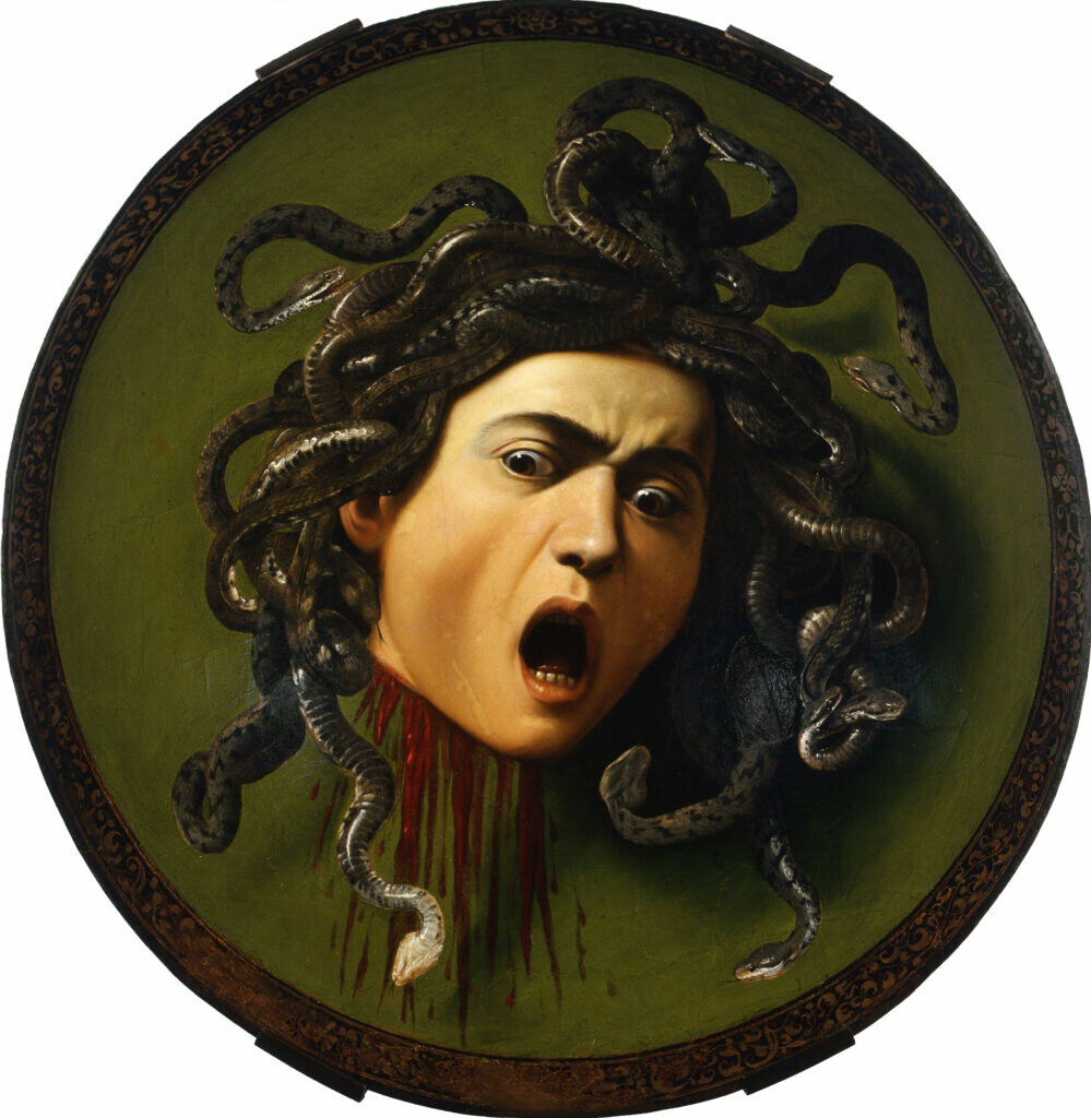 A circular framed painting of Medusa's severed head, eyes and mouth wide in surprise