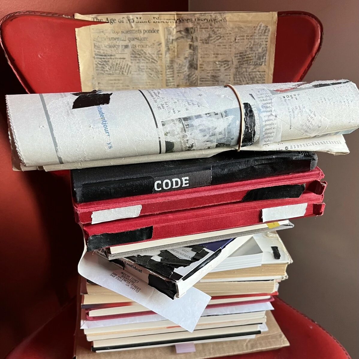 A red chair piled high with books and paper ephemera