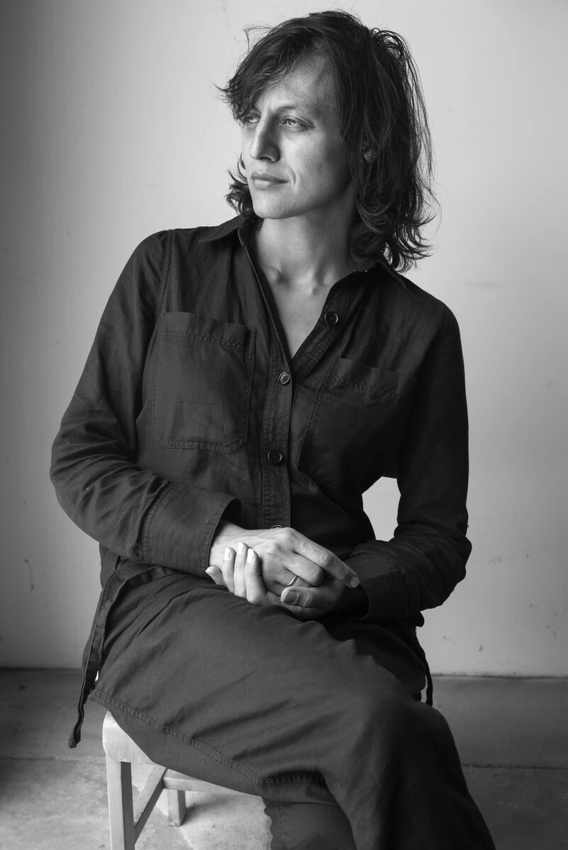 Black and white photo of a seated woman with her hands clasped on her lap