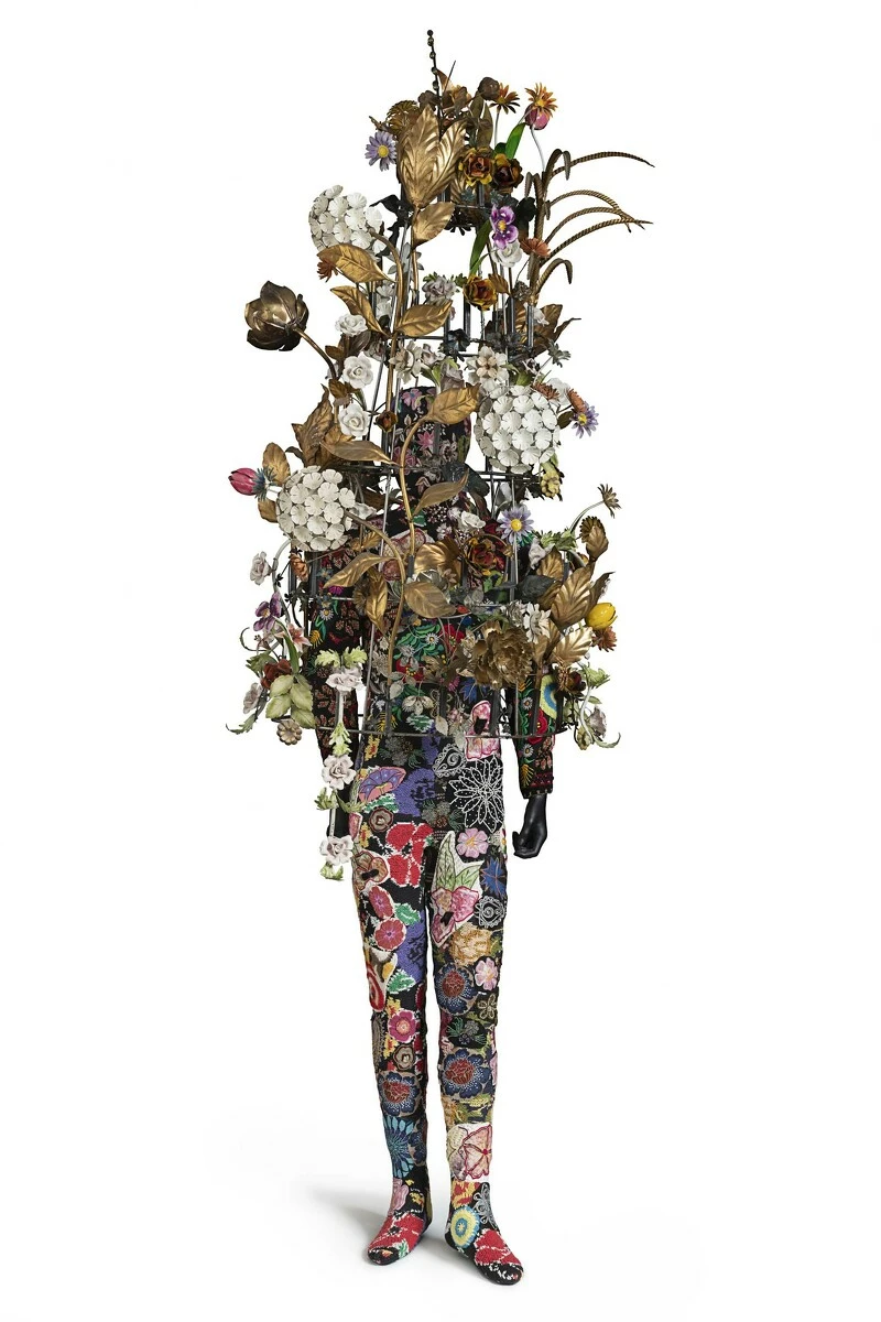 A mannequin form, but the top half consists of a large floral arrangement