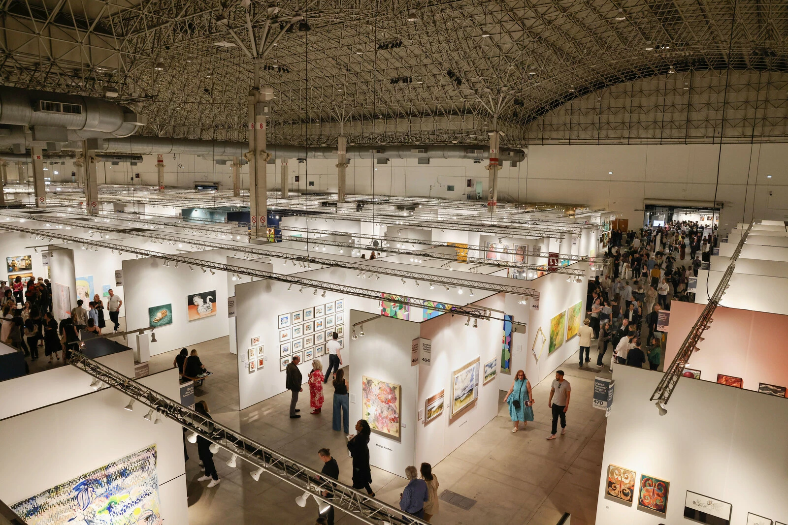 An overhead view of an art fair in a large, airy building.