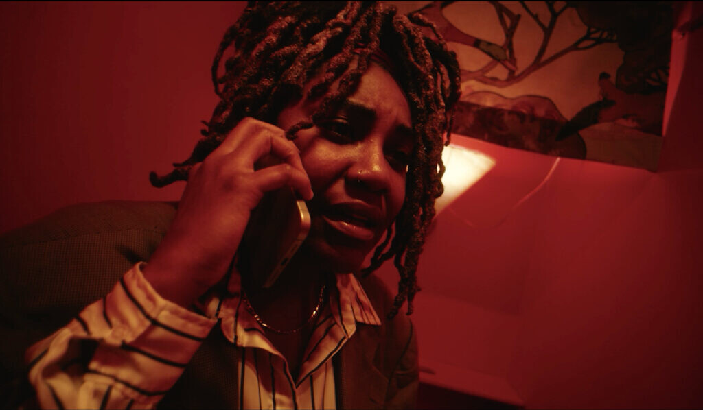 A red toned image of a person with a worried look on their face as they hold a cellphone up to their right ear