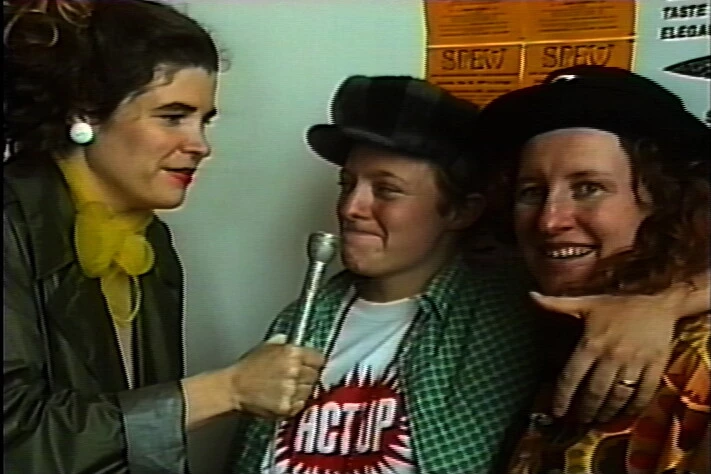 A grainy image of a person interviewing two people